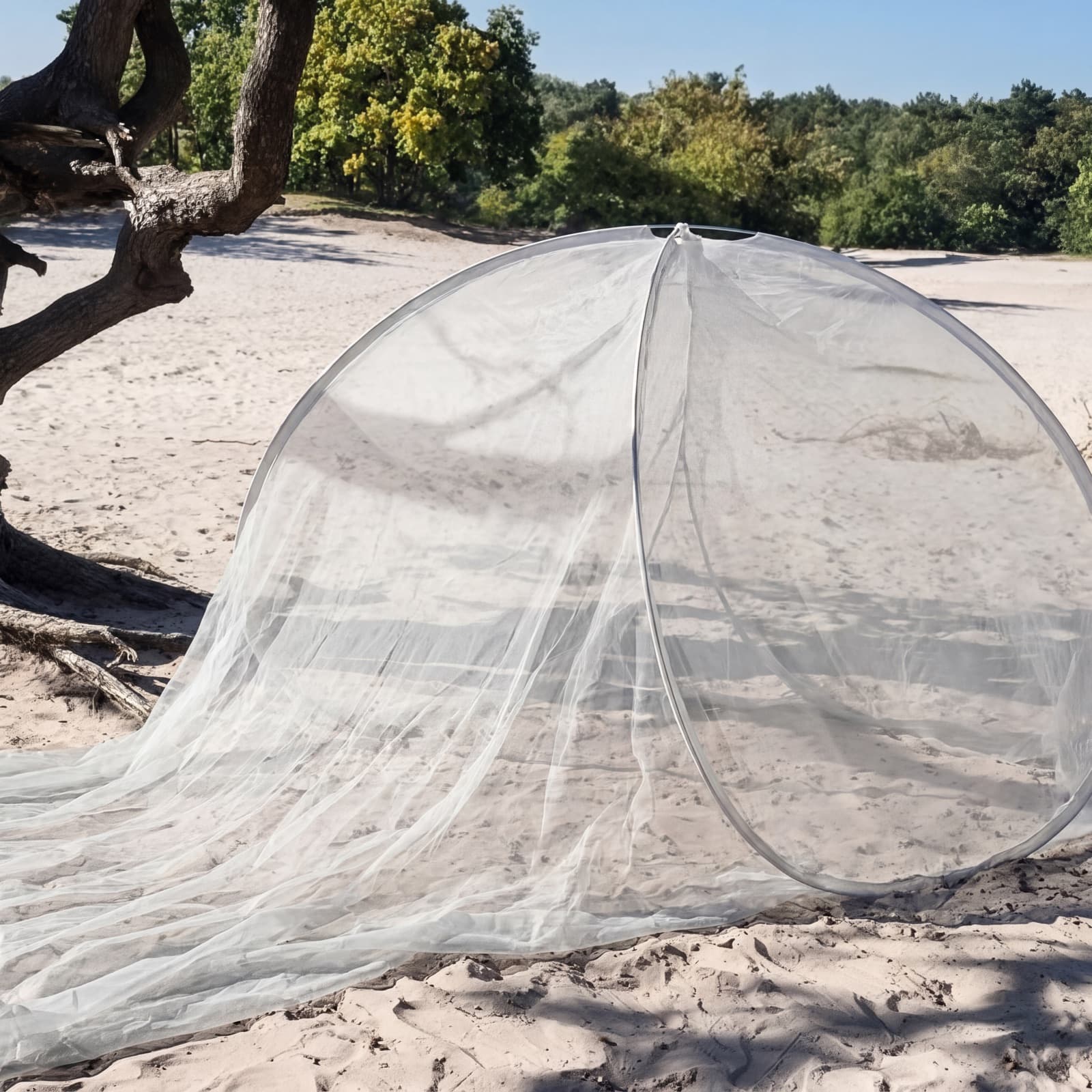 The Mosticare Domo Pop pop-up mosquito dome and groundsheet set up on a sandy beach by the sea.